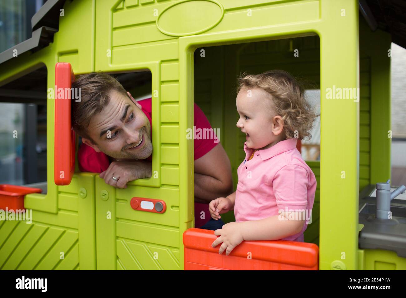 Glücklicher Vater spielt mit seinem Sohn in einem Gartenspielhaus. Fröhliches Kind genießt es, bei seinem Vater zu sein. Stockfoto