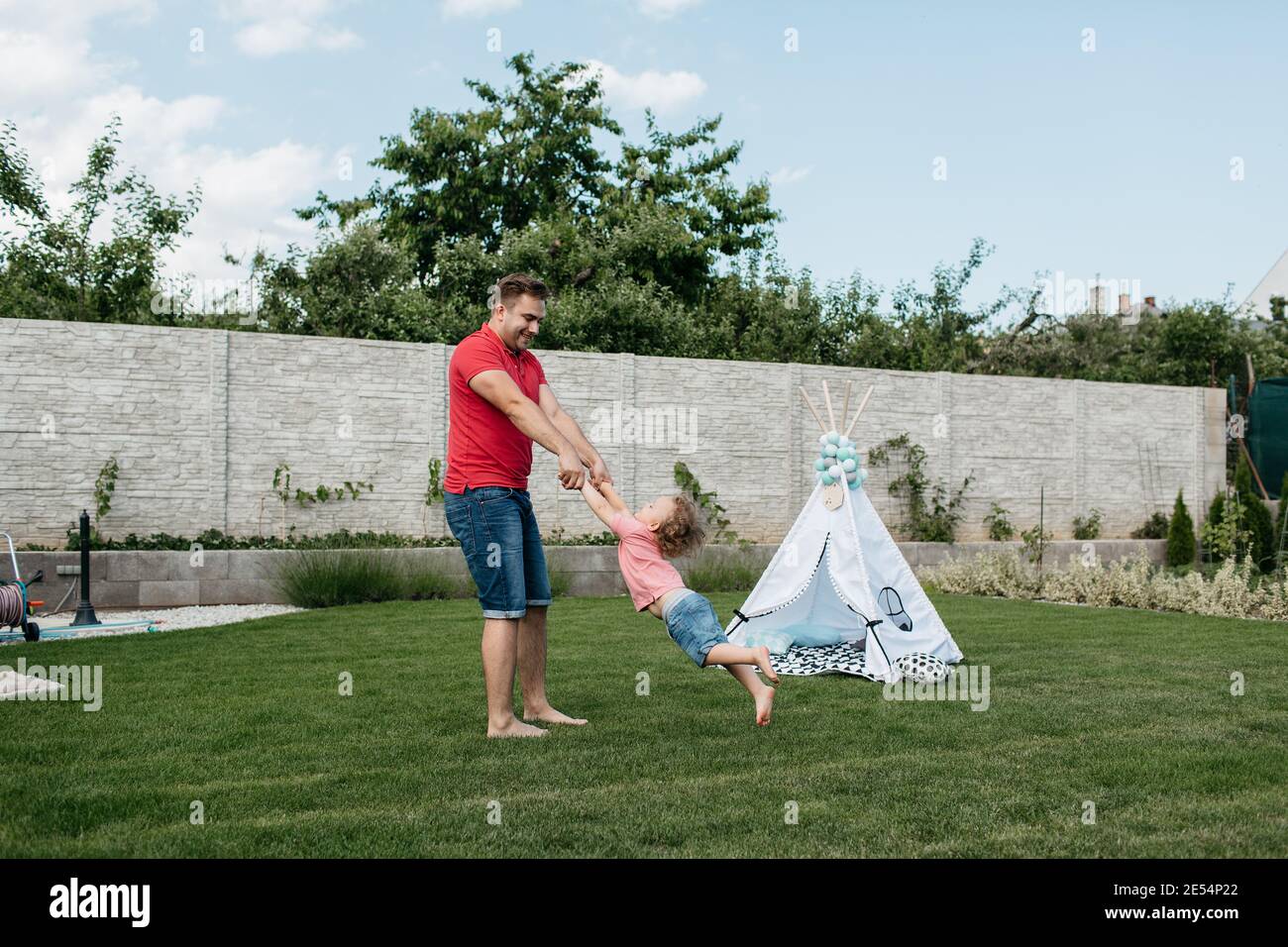 Fröhlicher Vater spielt mit seinem kleinen Sohn draußen im Garten. Glückliches Kind, das Spaß mit seinem Vater hat. Stockfoto