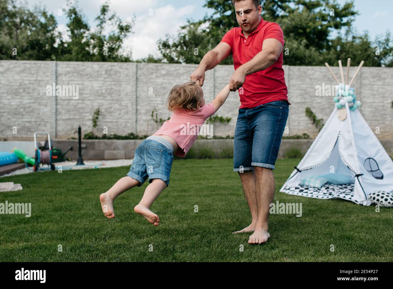 Vater dreht seinen kleinen Sohn draußen im Garten. Glückliches Kind, das Spaß mit seinem Vater hat. Stockfoto