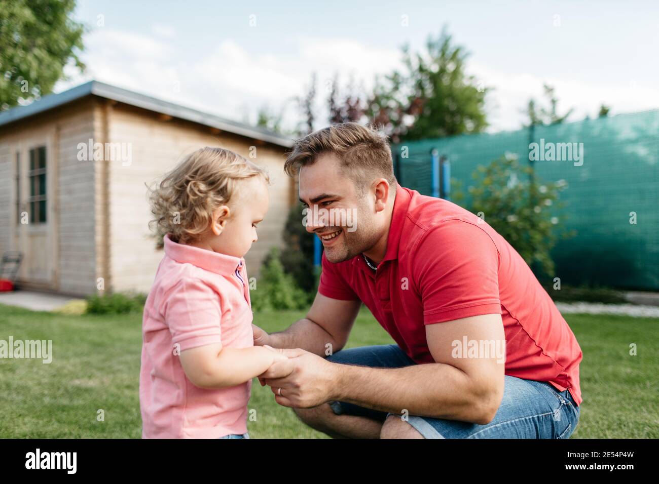 Glücklicher Vater schaut mit Liebe auf seinen Sohn draußen im Garten. Kind Spaß mit seinem Vater an einem sonnigen Sommertag. Stockfoto