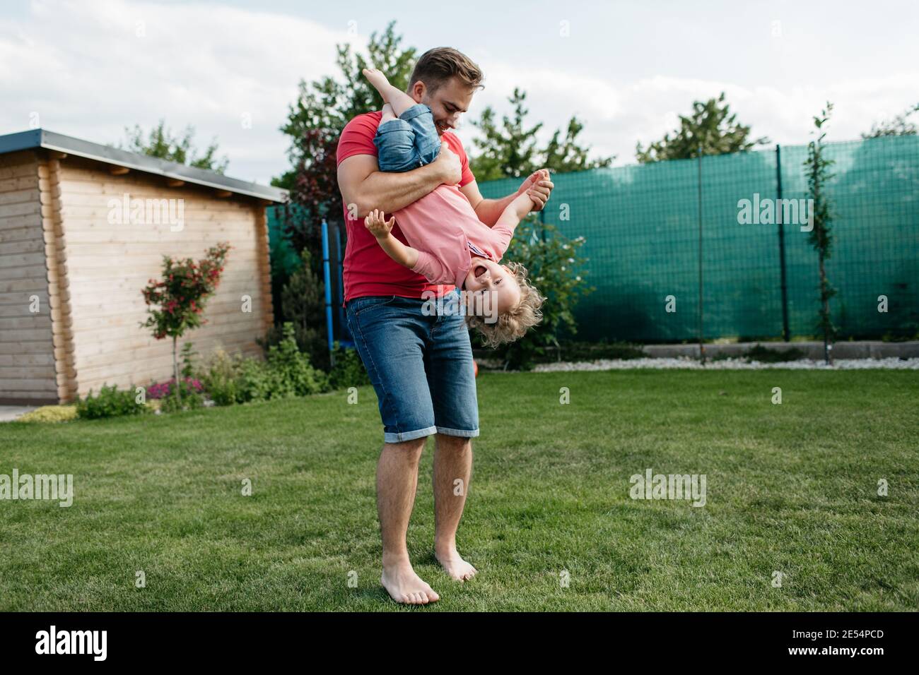 Vater spielt mit seinem Sohn draußen im Garten. Glückliches Kind, das Spaß mit seinem Vater hat. Stockfoto