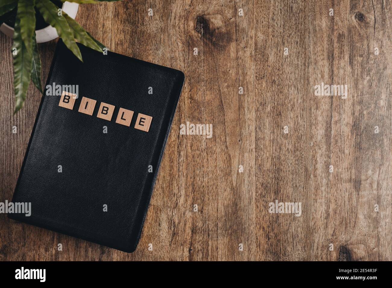 Wortbibel in Blockbuchstaben auf einer bibel auf einem Holztisch.Draufsicht flach liegend. Stockfoto