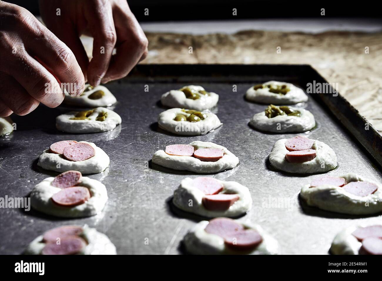 Hand eines Bäckers beim Platzieren von Mini-Pizza auf dem Backblech Stockfoto