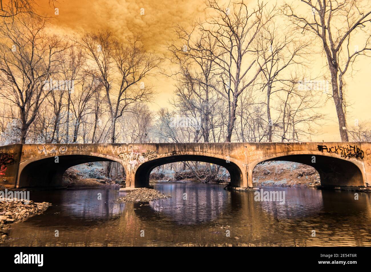 Eine dreibogenige Betonbrücke mit vielen Graffiti, die Guthrie Creek im westlichen Jackson County Indiana überspannt. Falschfarben-Infrarot-Iamge. Stockfoto