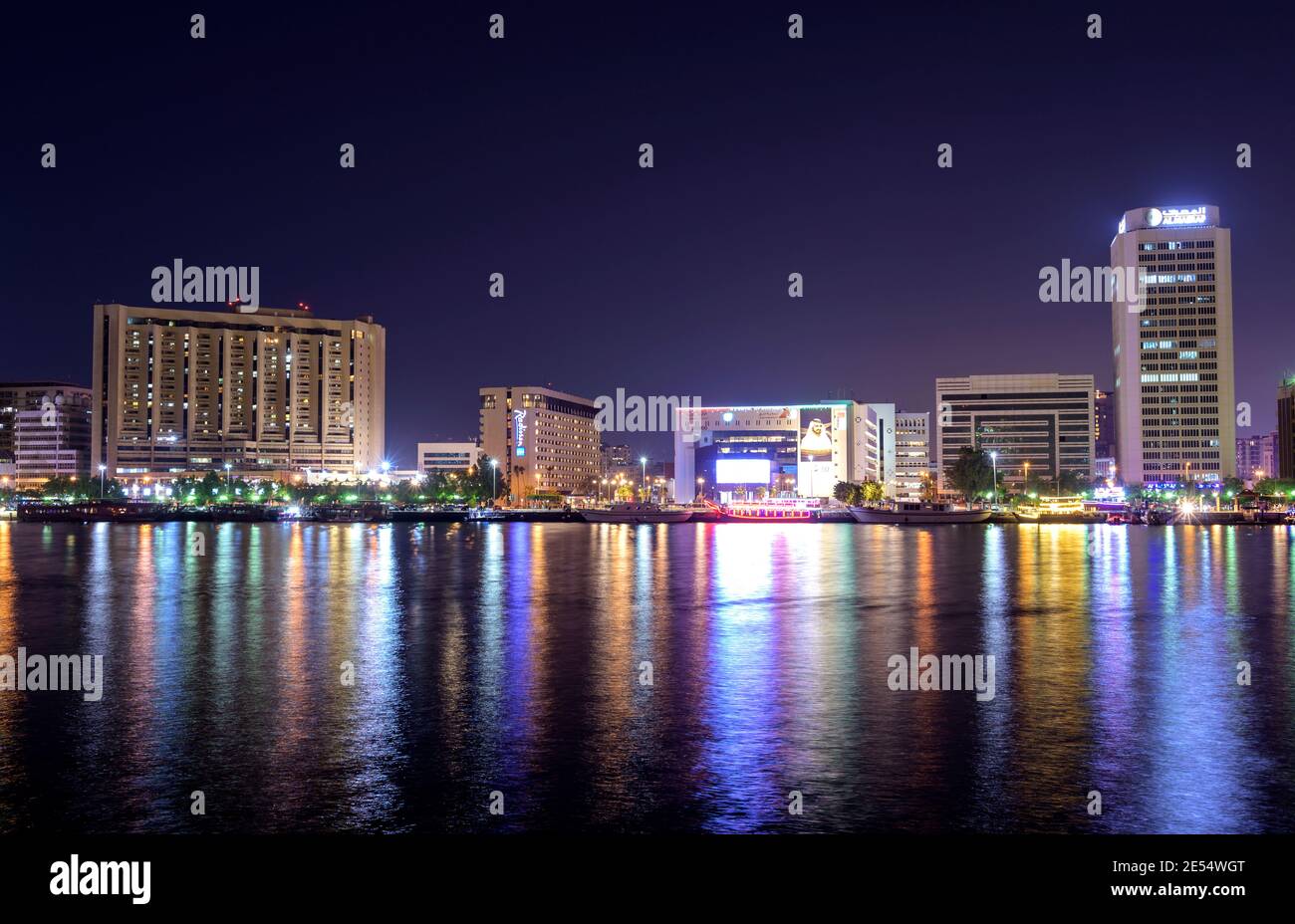 Panaromischer Blick auf die beleuchteten Himmel Scrappers, Hotels und Gebäude zeigen wunderschöne Reflexionen im Wasser im Al Seef, Dubai, VAE gefangen. Stockfoto