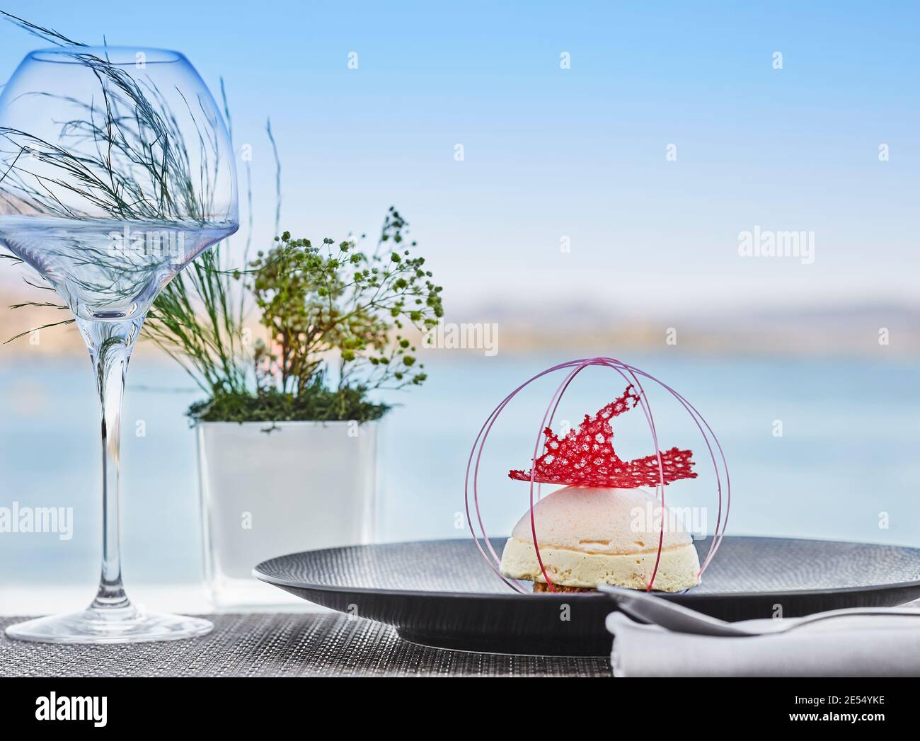 Dessert mit Speiseeis und roter Karamelldekoration Tisch mit Meerblick Stockfoto
