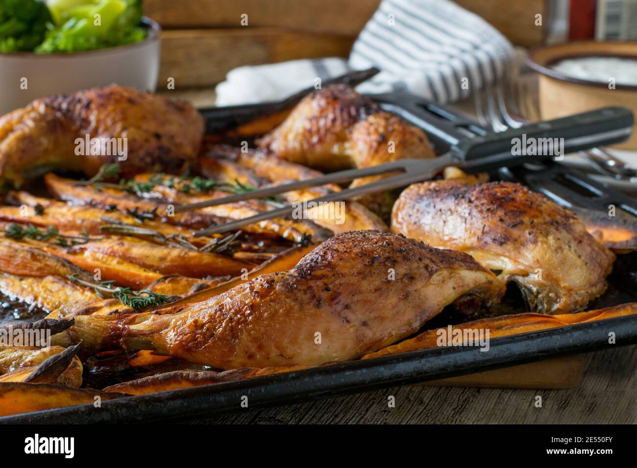 Gebratenes Hähnchen mit Süßkartoffelfrites auf einem Backblech Stockfoto