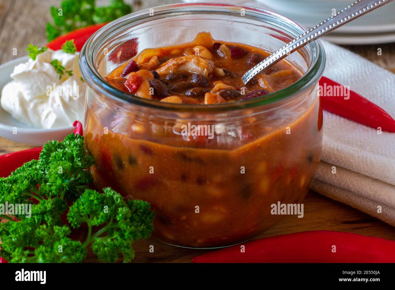 Frisch gekochte Bohnensuppe mit Hühnerfleisch serviert Glasschale auf Holztisch Stockfoto