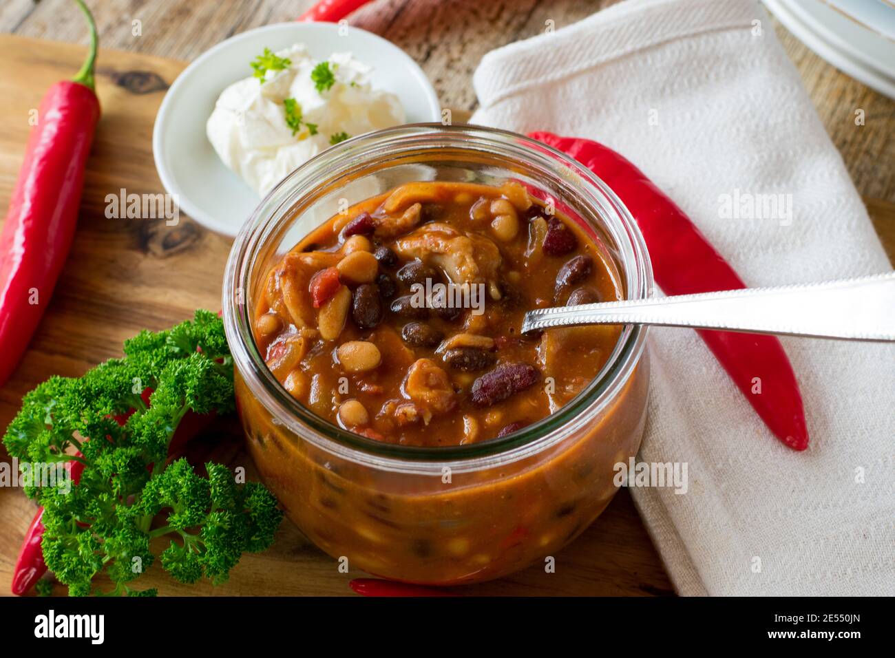 Frisch gekochte Bohnensuppe mit Hühnerfleisch serviert Glasschale auf Holztisch Stockfoto