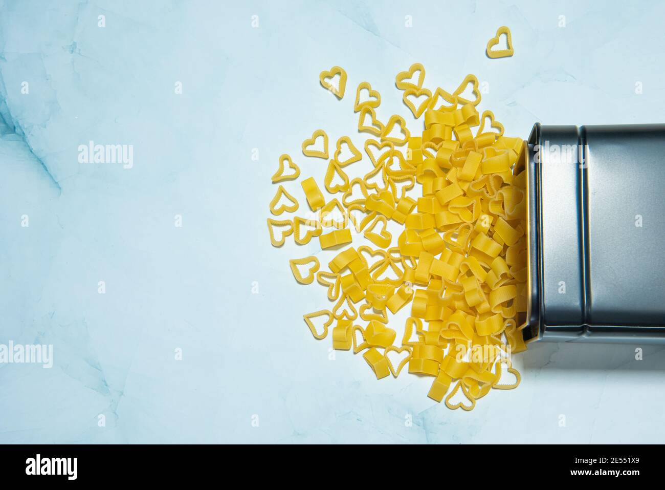 Essen Hintergrund und valentine-Konzept. Pasta in Herzform auf blauem Marmorboden. Konzept der Pasta-Liebhaber. Pasta verschüttet aus der Box. Hochwertige Fotos Stockfoto