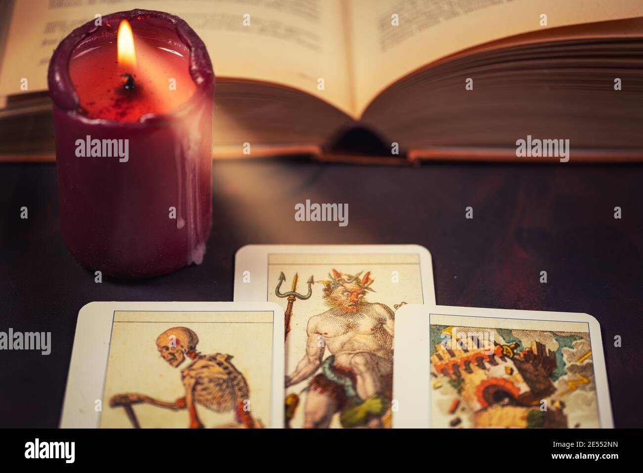 Tarot-Karten mit Kerzenlicht und Buch auf dem dunklen Hintergrund, Halloween und zukünftige Lesekonzept. Stockfoto