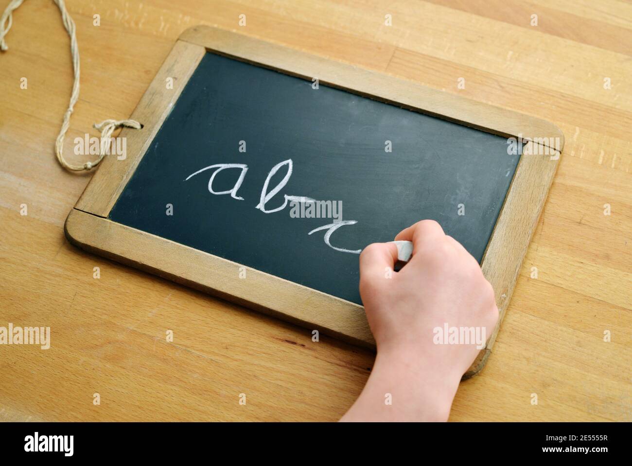 Kinderhand schreibt abc auf eine Tafel mit Kreide Stockfoto