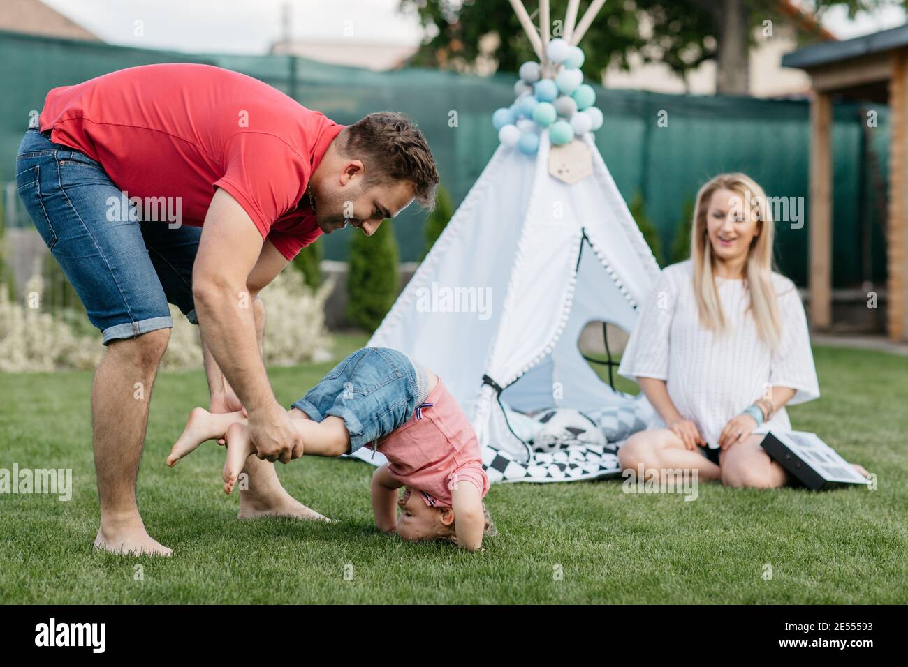 Glückliche Familie verbringen Zeit zusammen draußen im Garten. Kind Spaß mit seinen Eltern und spielen auf dem Rasen. Stockfoto