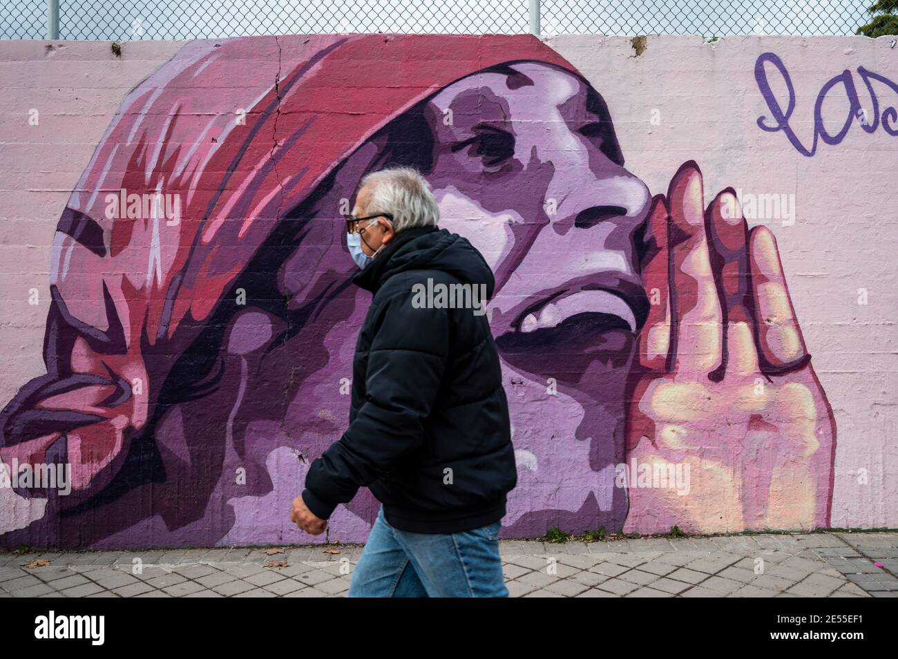 Madrid, Spanien. Januar 2021. Ein Mann mit Gesichtsmaske zum Schutz vor der Ausbreitung des Coronavirus (COVID-19) geht an einem feministischen Wandgemälde mit dem Namen 'Union macht Kraft' vorbei. Die rechtsextreme Partei VOX schlug vor, das Wandgemälde zu entfernen, das schließlich nicht entfernt werden wird, da die Partei Ciudadanos seine Stimme geändert hat. In der Wandmalerei erscheinen die Gesichter von 15 Frauen, die für ihren Kampf für die Gleichheit Teil der Geschichte sind. Quelle: Marcos del Mazo/Alamy Live News Stockfoto