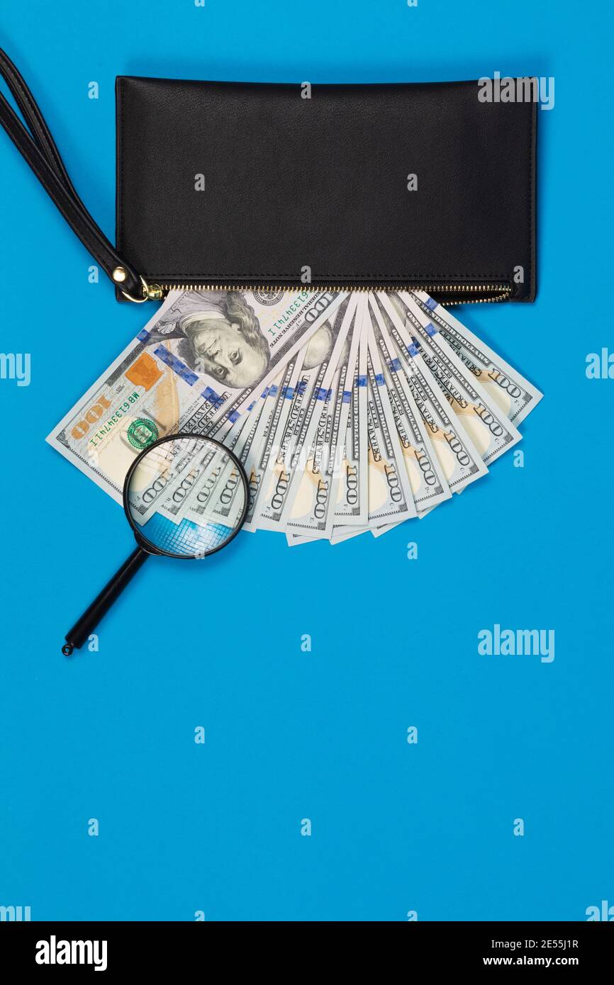 Schwarze Brieftasche mit hundert Dollar Scheinen auf einem blauen Hintergrund Stockfoto