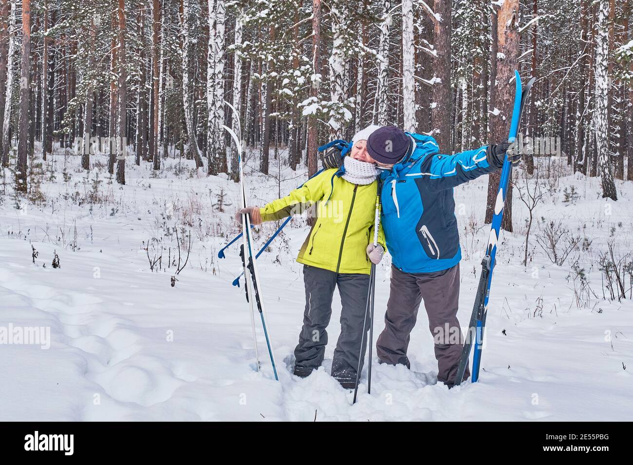 Glückliches reifes Paar im Winter Sportbekleidung mit Langlaufski küssen Im verschneiten Wald Stockfoto