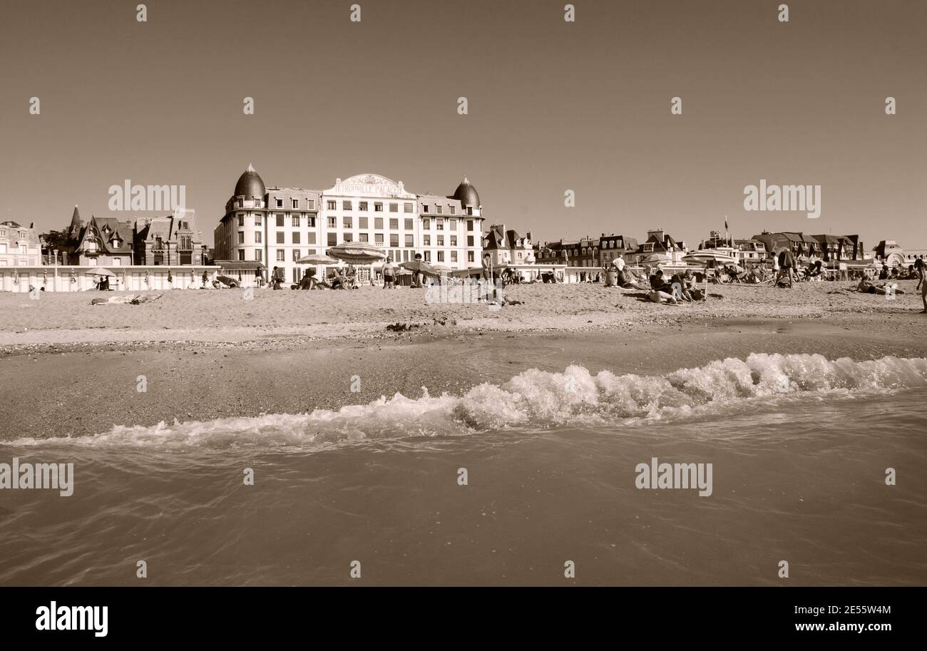 Die Leute entspannen sich am Strand. Trouville-sur-Mer und das nahe gelegene Deauville sind beliebte Sommerresorts in der Normandie. Sepia historisches Foto Stockfoto