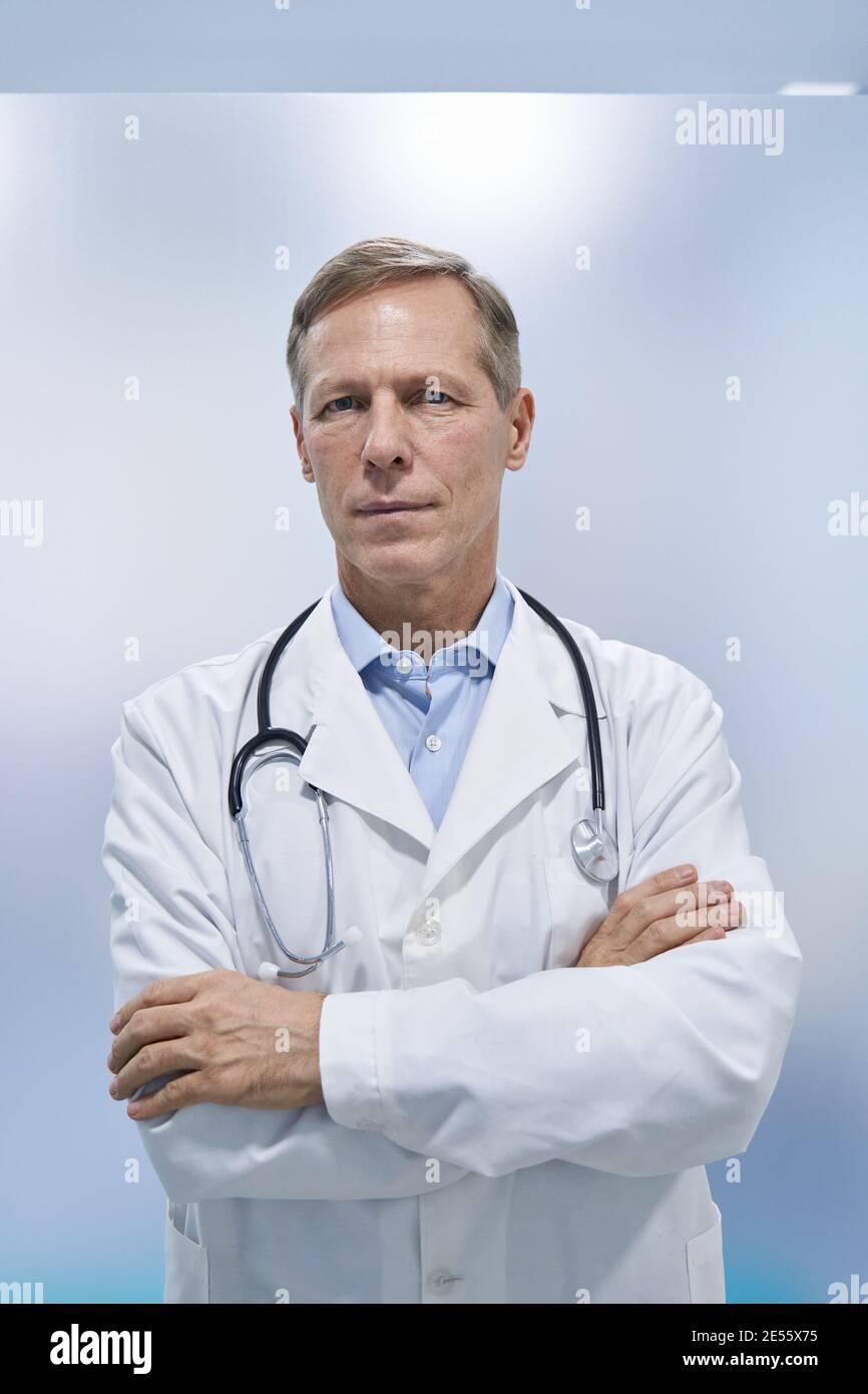 Selbstbewusste ältere professionelle Arzt stehende Arme gekreuzt Blick auf die Kamera. Stockfoto