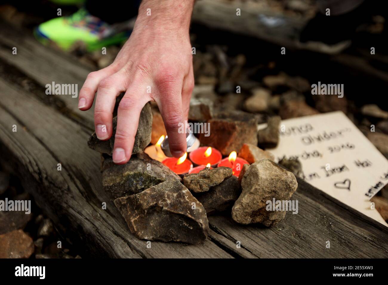 Oswiecim, Polen - 5. Mai 2016: März des Lebens in Oswiecim, im Staatlichen Museum Auschwitz-Birkenau. Der Mann zündet Kerzen in der Nähe der Baracke an Stockfoto
