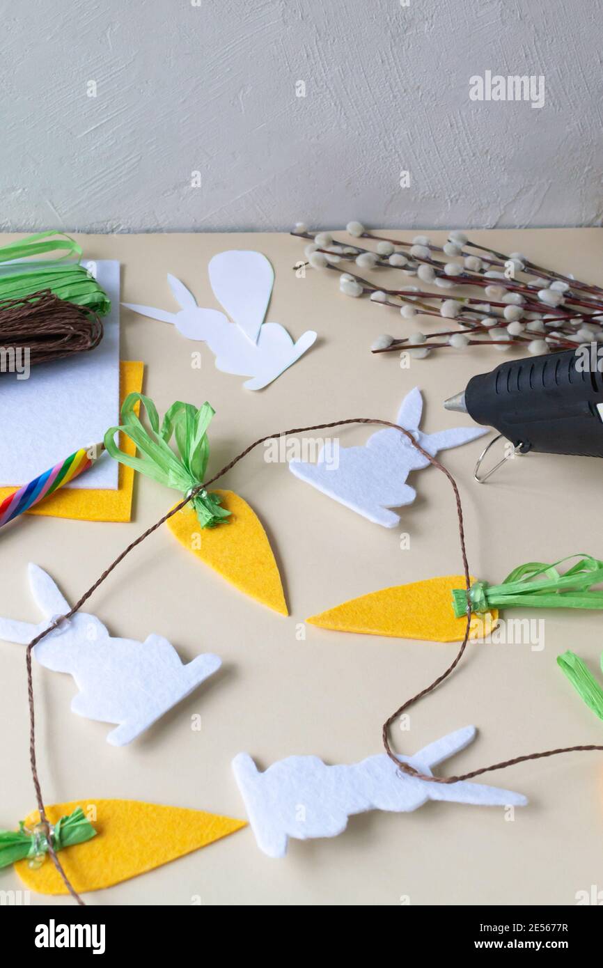 Wie man eine Ostergirlande aus Kaninchen und Karotten mit eigenen Händen aus Filz macht. Schritt-für-Schritt-Anleitung. Schritt 10. Wir setzen alle Elemente auf ein br Stockfoto