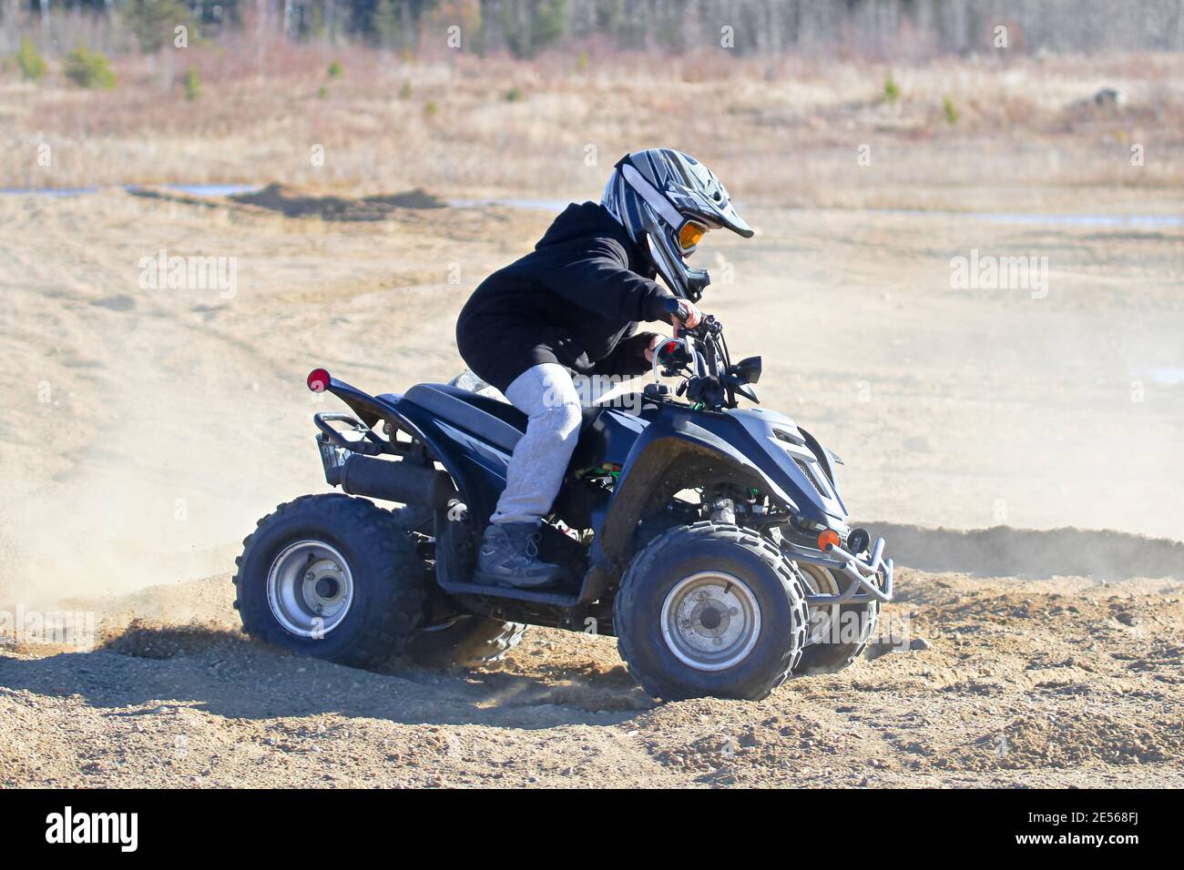 Ein kleiner Junge auf seinem atv mit einem staubigen Hintergrund Stockfoto