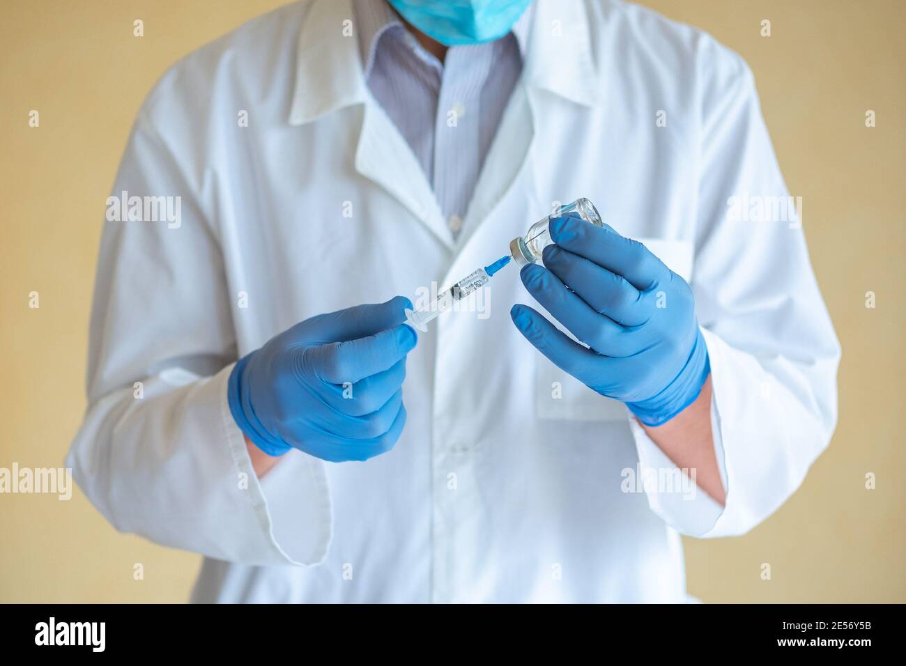 Arzt Mann in blauen Latexhandschuhen wählt einen Impfstoff in Eine Nahaufnahme der Spritze Stockfoto