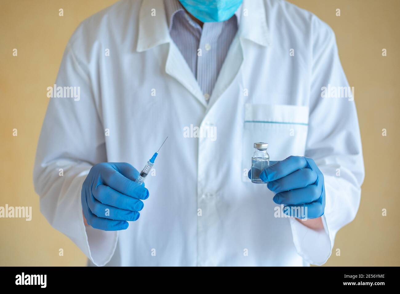 Arzt Mann in blauen Latexhandschuhen hält Spritze und Ampulle Mit Nahaufnahme des Impfstoffes Stockfoto