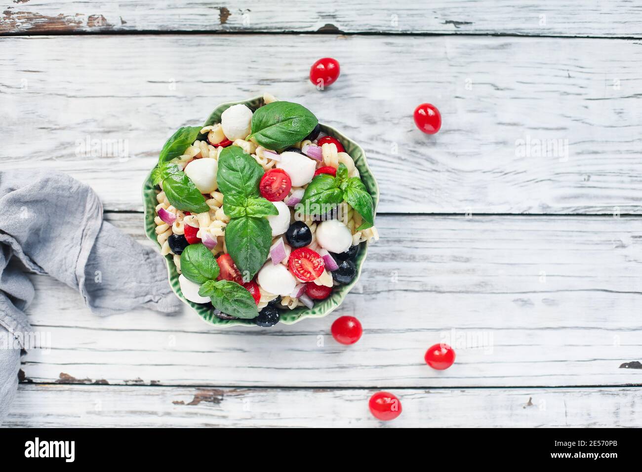 Italienischer Nudelsalat mit frischen Tomaten, schwarzen Oliven, roten Zwiebel Mozzarella Käsebällchen, Basilikum und einem Olivenöl-Dressing. Bild von oben aufgenommen. Stockfoto