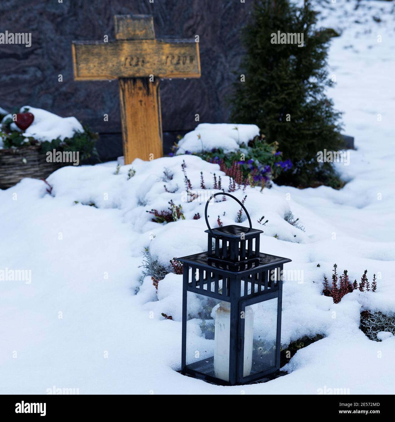 Grablicht auf einem schneebedeckten Grab mit dem Einkreuzen Hintergrund Stockfoto