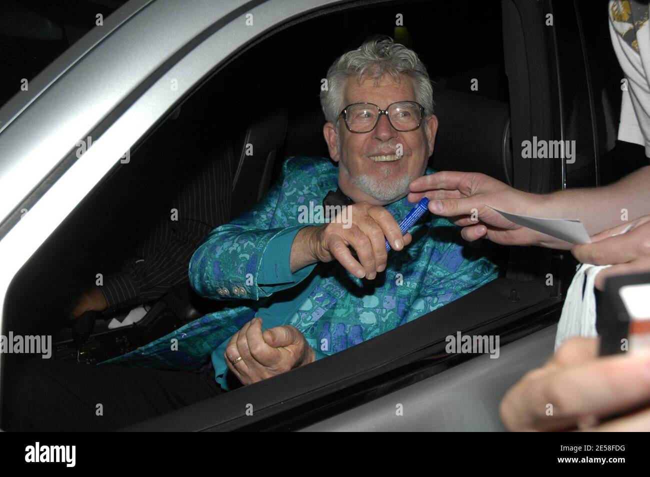 Der australische Musiker, Komponist, Maler und Fernsehmoderator Rolf Harris hält an, um bei Barbara Windsor's 70. Geburtstagsparty im Royal Garden Hotel ein Autogramm zu unterschreiben. London, Großbritannien. 07. [[Karte]] Stockfoto