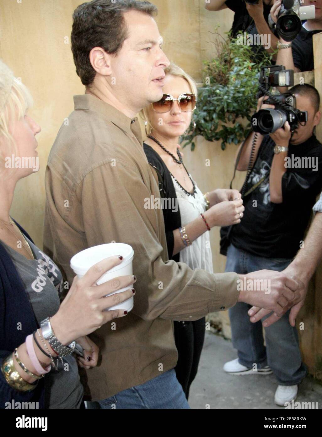 Lindsay Lohan war zwar während der Reha für zwei Monate aus dem Limonenlicht heraus, hat aber ihren Platz in den Reihen der Must-Have-Celebrity-Fotos nicht verloren. Lohan machte sich den Weg durch eine riesige Schar von Fotografen, als sie Orso nach dem Mittagessen heute verlassen. Lindsay schien sich jedoch nicht um die Aufmerksamkeit zu kümmern, da sie zu grinsen schien, als sie sich hinter ihrem Wachmann versteckte. Los Angeles, Kalifornien, 10/17/07. [[rac ral]] Stockfoto