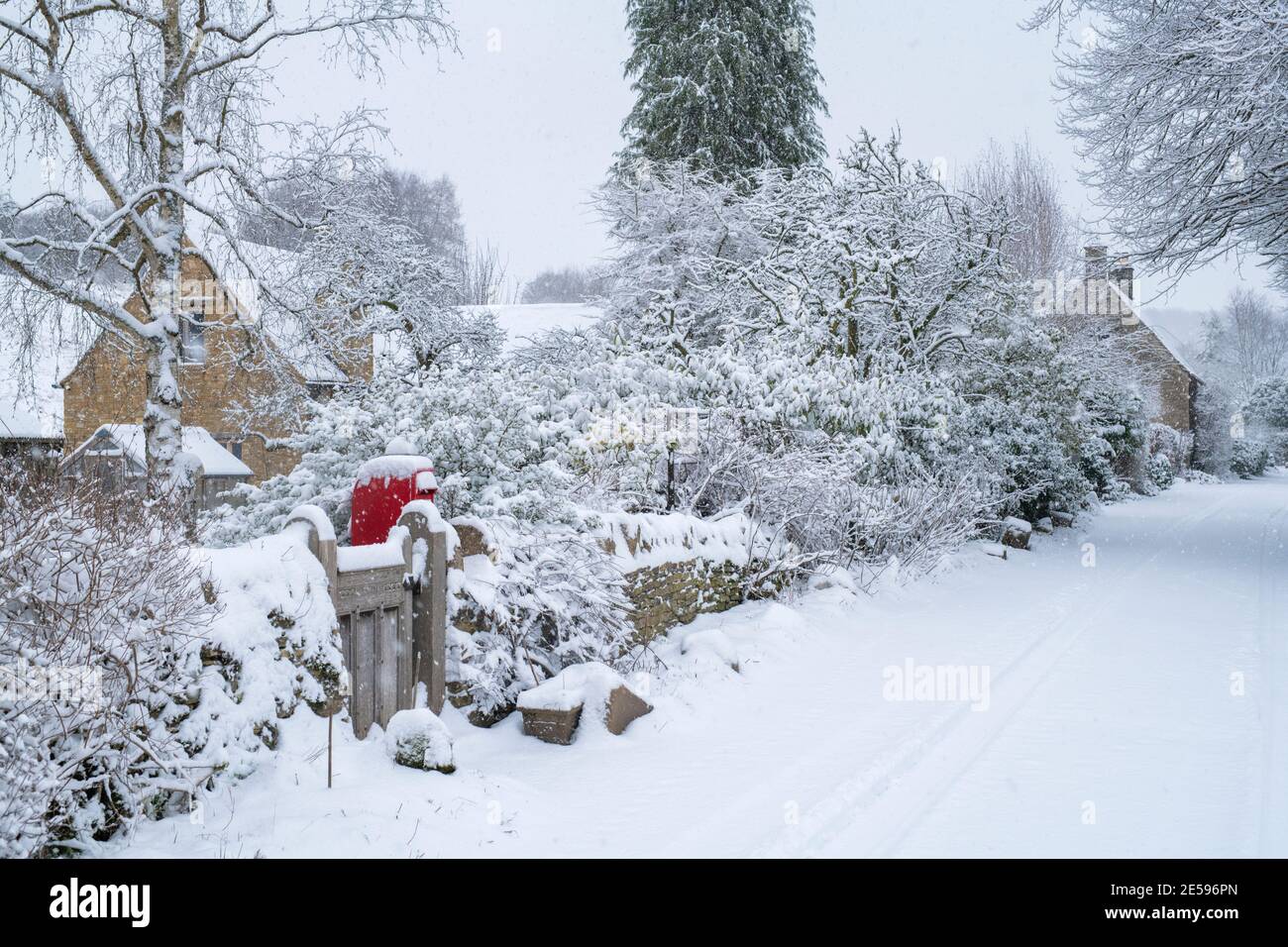 Landstraße und cotswold Steinhütten in Swinbrook im Schnee. Swinbrook, Cotswolds, Oxfordshire, England Stockfoto