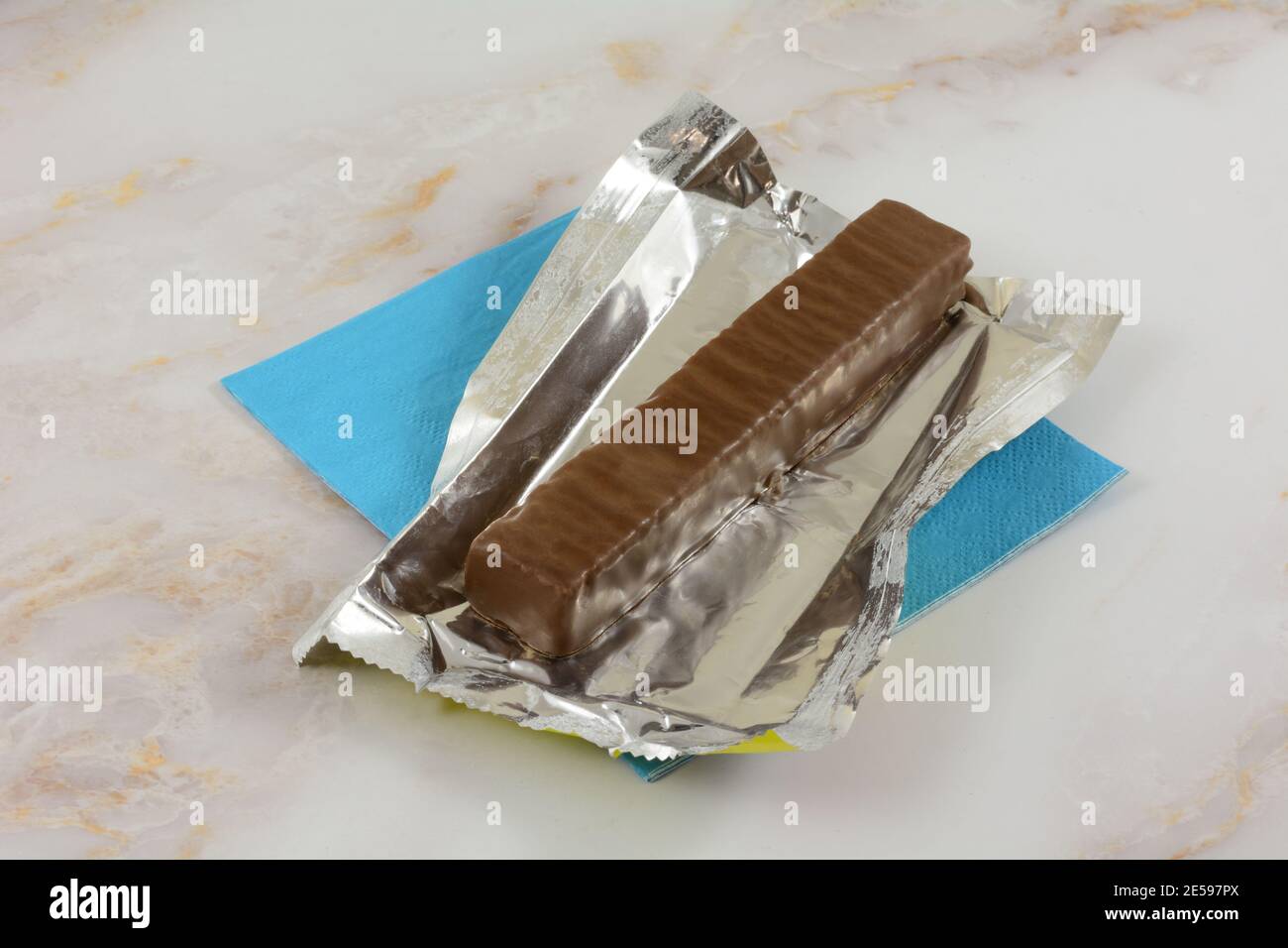 Schokoriegel in geöffneter Folienverpackung auf blauer Serviette Stockfoto