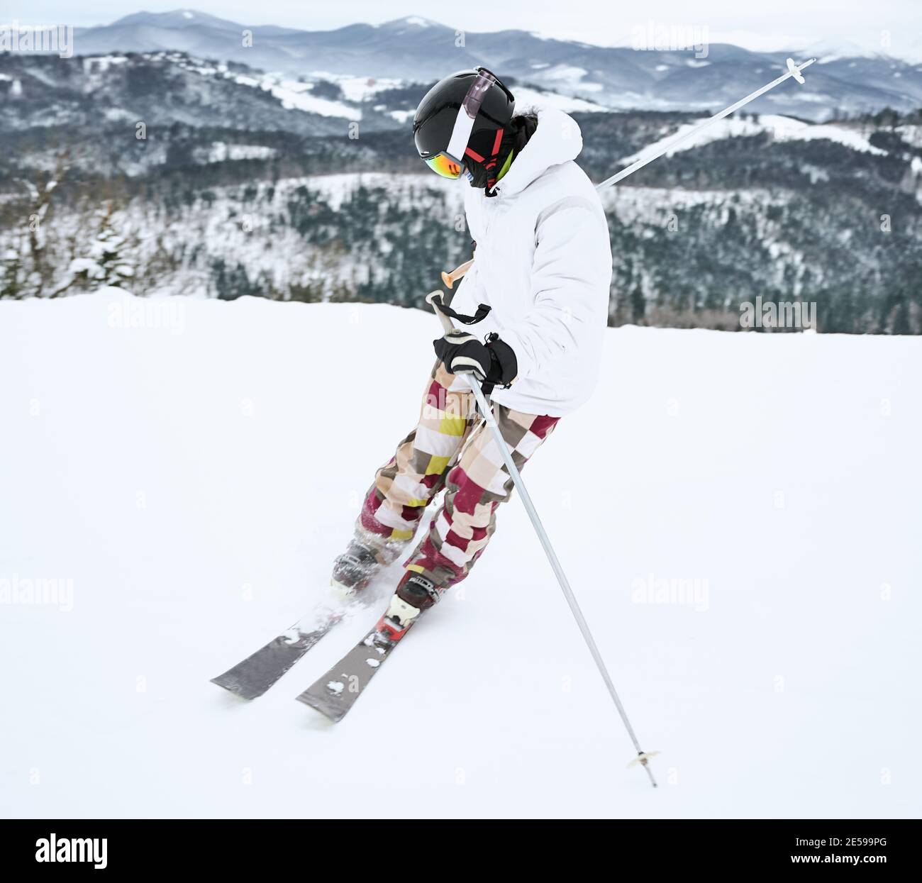 Bild von Skifahrer in Skiausrüstung, in Bewegung gefangen dabei Trick in verschneiten Bergen in voller Länge. Schöne Landschaft im Hintergrund. Wintersportkonzept Stockfoto