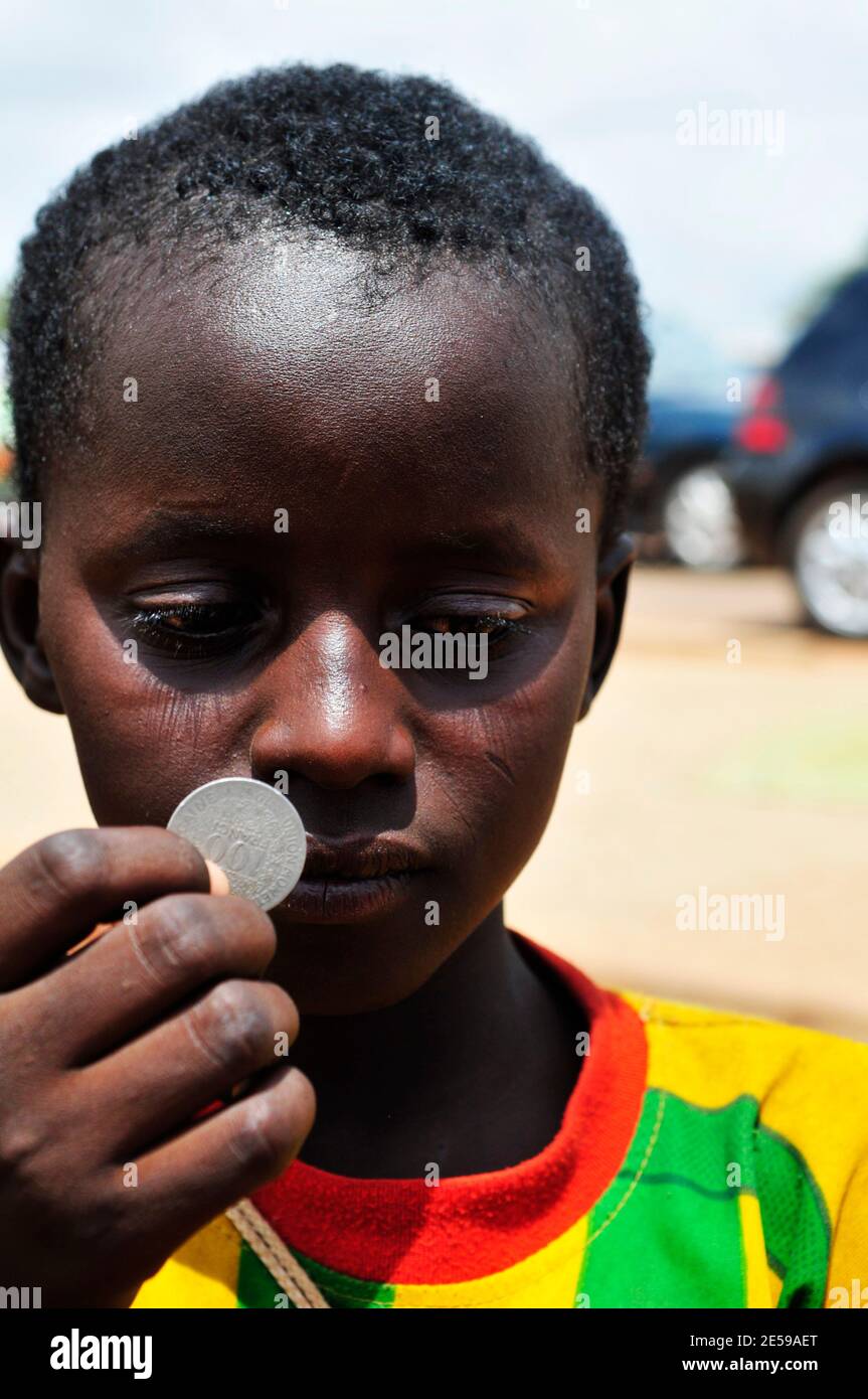 Ein burkinischer Junge mit einer Westafrikanischen Frankenmünze von 100. Stockfoto