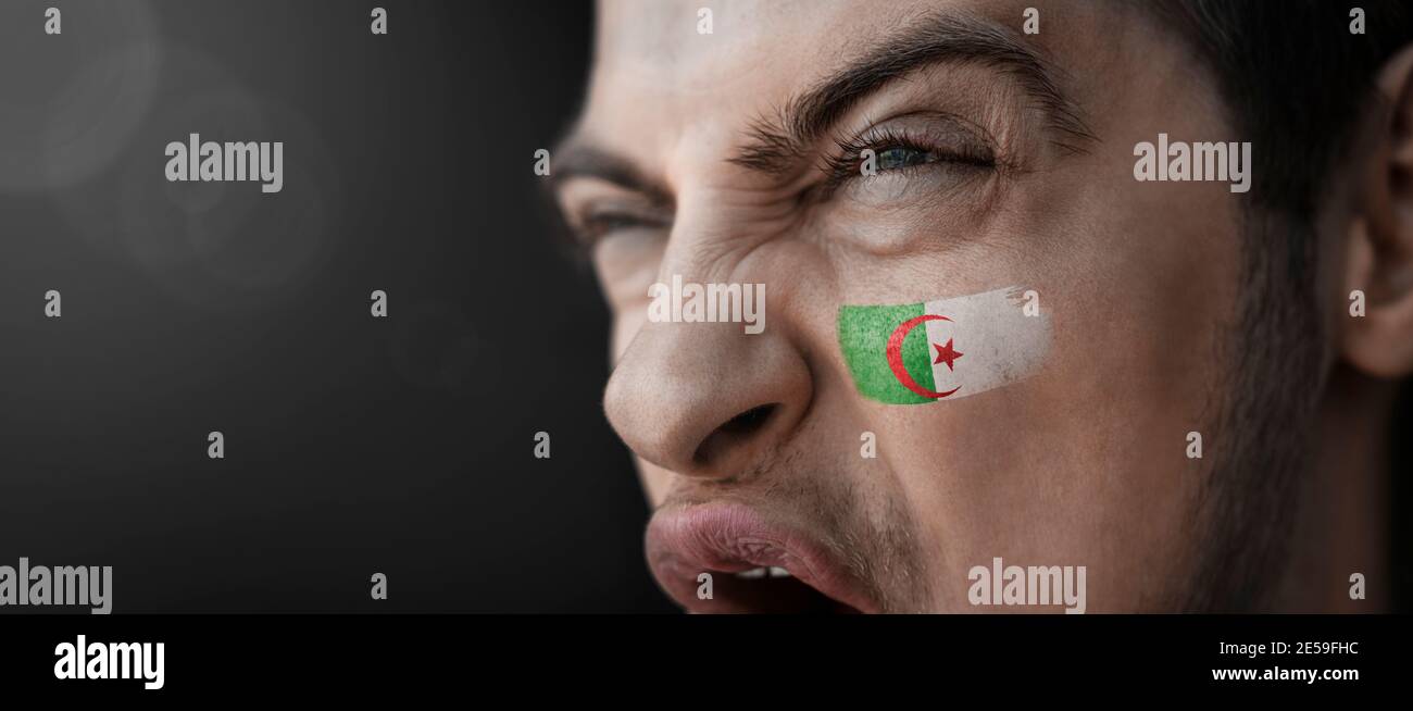 Ein schreiender Mann mit dem Bild des algerischen Nationales Flagge auf seinem Gesicht Stockfoto