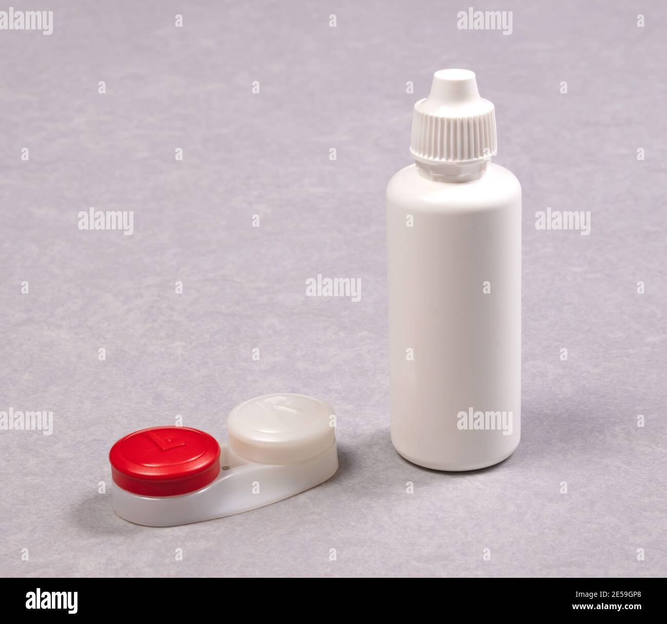 Rotes Kontaktlinsengehäuse und Flasche mit Lösung, isoliert auf grauem Hintergrund Stockfoto