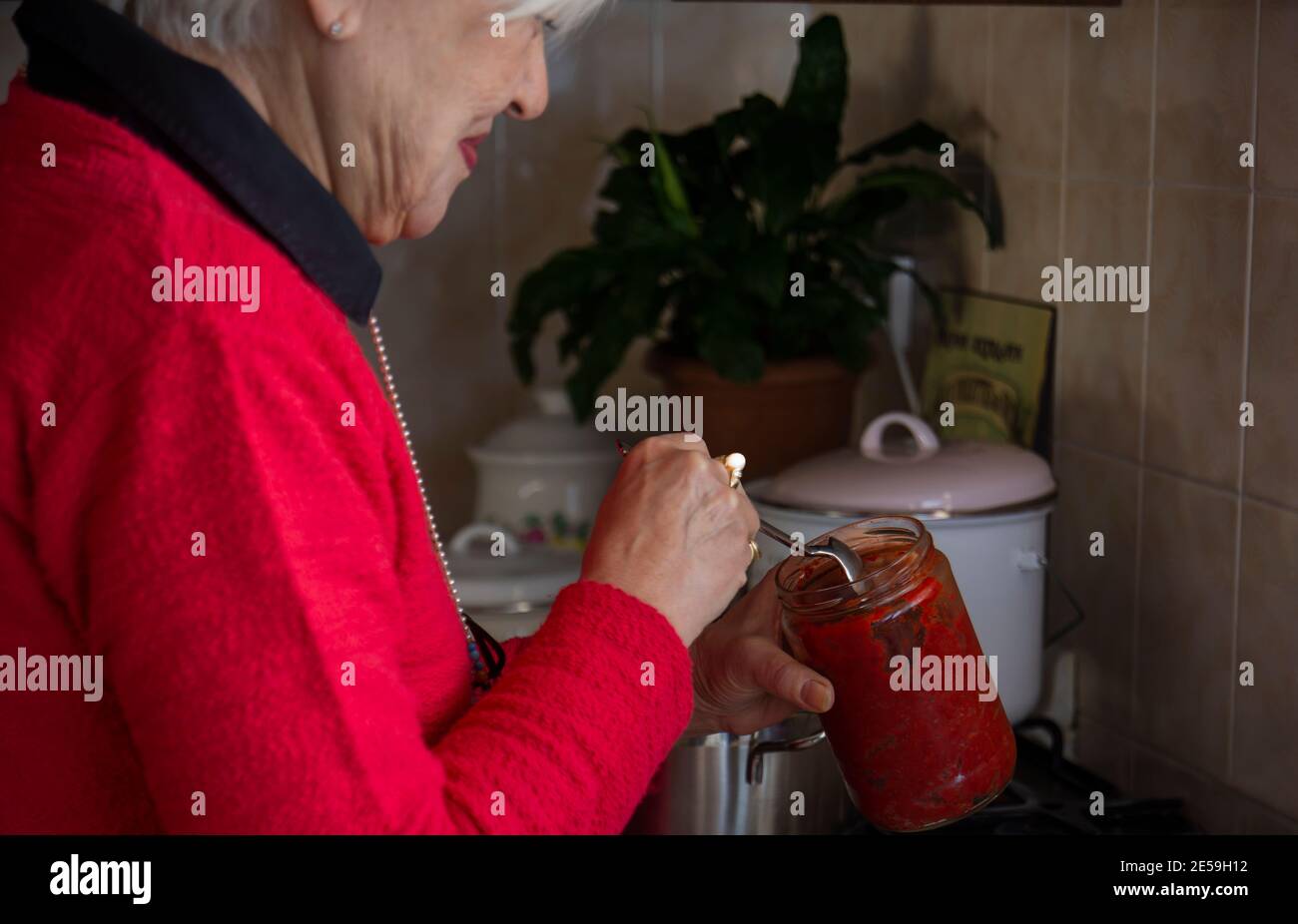 Frau im roten Pullover macht Suppe in der Küche. Selektiver Fokus Frau in rotem Pullover. Traditionelle türkische Seife tarhana. Stockfoto