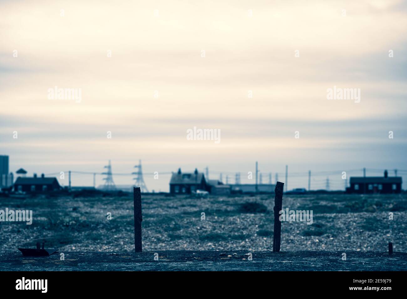 Häuser und Pylons mit großem Himmel am Dungeness Strand. Kent, England. Stockfoto