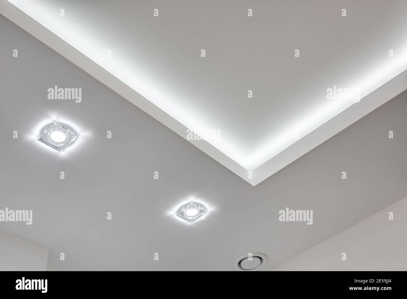 Abgehängte Decke mit Halogenstrahlern und Trockenmauerkonstruktion im leeren Raum in Wohnung oder Haus. Stretchdecke weiß und komplex. Stockfoto