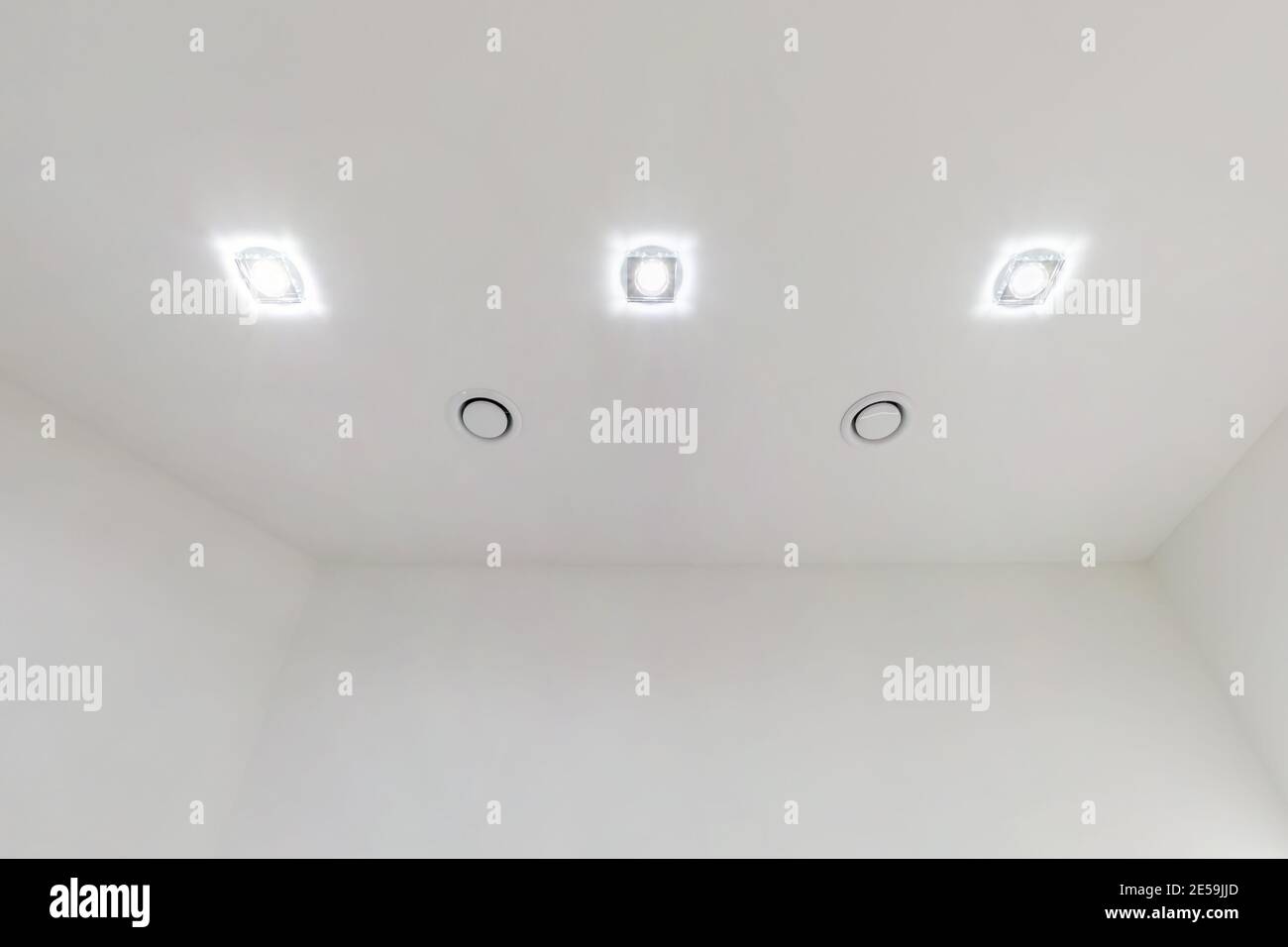 Abgehängte Decke mit Halogenstrahlern und Trockenmauerkonstruktion im leeren Raum in Wohnung oder Haus. Stretchdecke weiß und komplex. Stockfoto