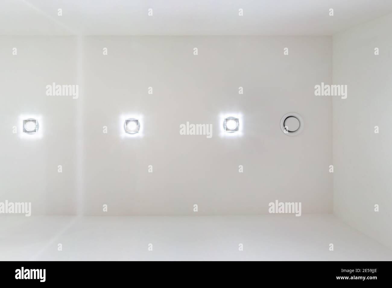 Abgehängte Decke mit Halogenstrahlern und Trockenmauerkonstruktion im leeren Raum in Wohnung oder Haus. Stretchdecke weiß und komplex. Stockfoto