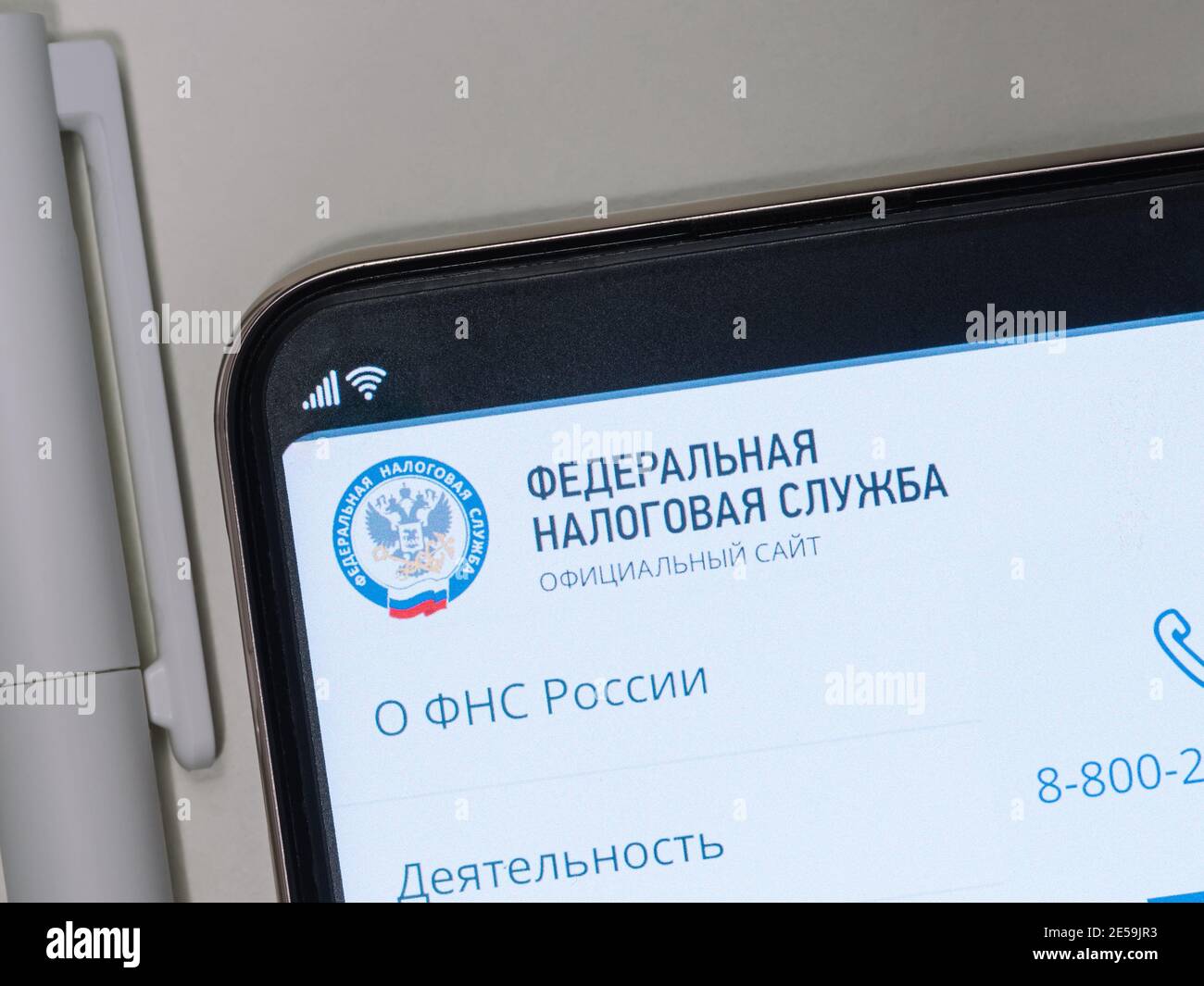 Moskau, Russland - 25. Januar 2021: Website der Federal Tax Service of Russia auf Smartphone-Bildschirm über weißen Tisch, in der Nähe Stift Stockfoto