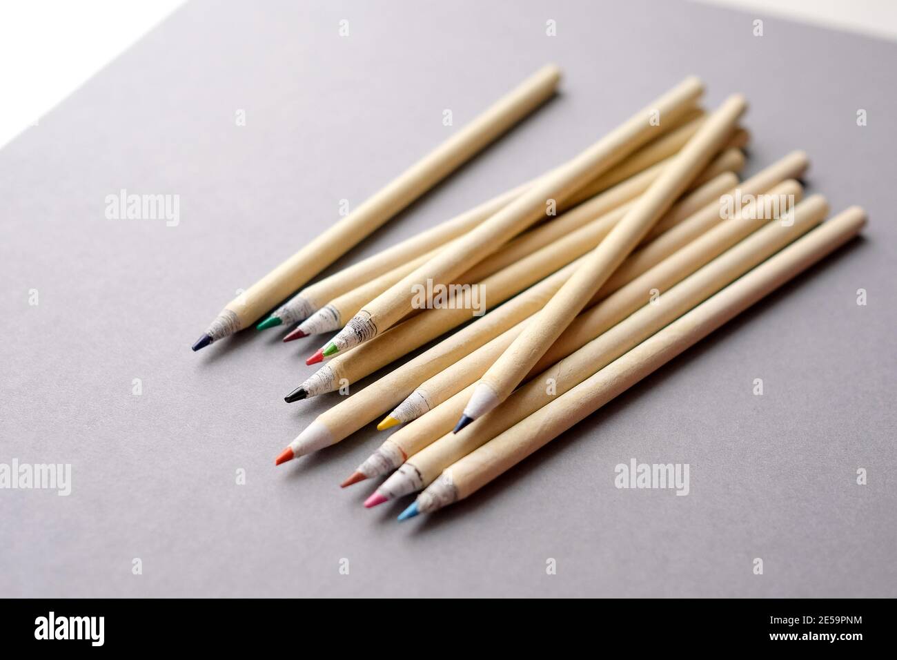 Umweltfreundliche Bleistifte auf grauem Hintergrund. Farbige wiederverwertbare Buntstifte. Mehrere Buntstifte liegen auf grauem Papier. Stockfoto