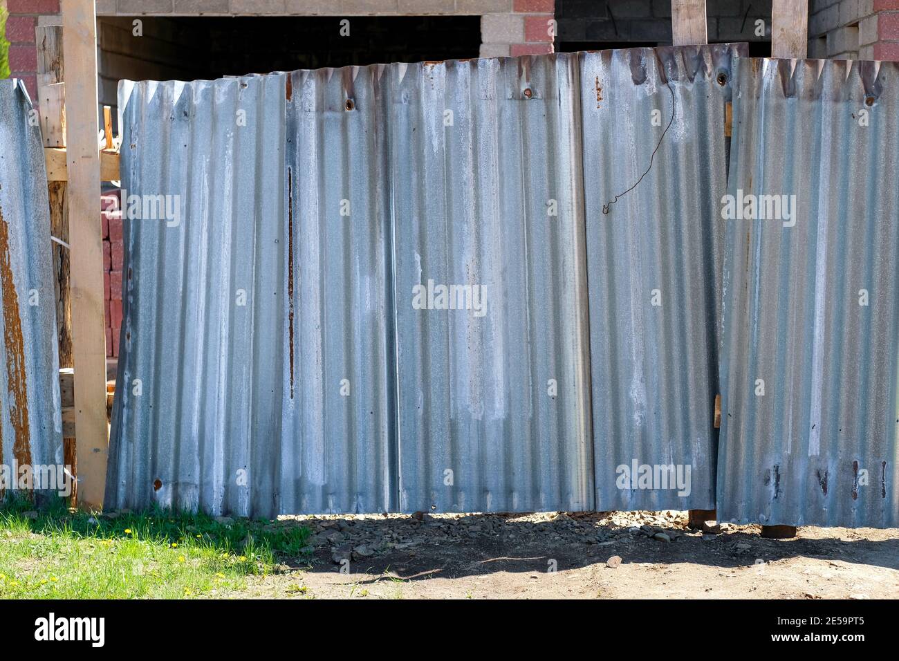 Ein alter klappriger Zaun aus Aluminium und Holz. Eiserner Ringzaun. Stockfoto