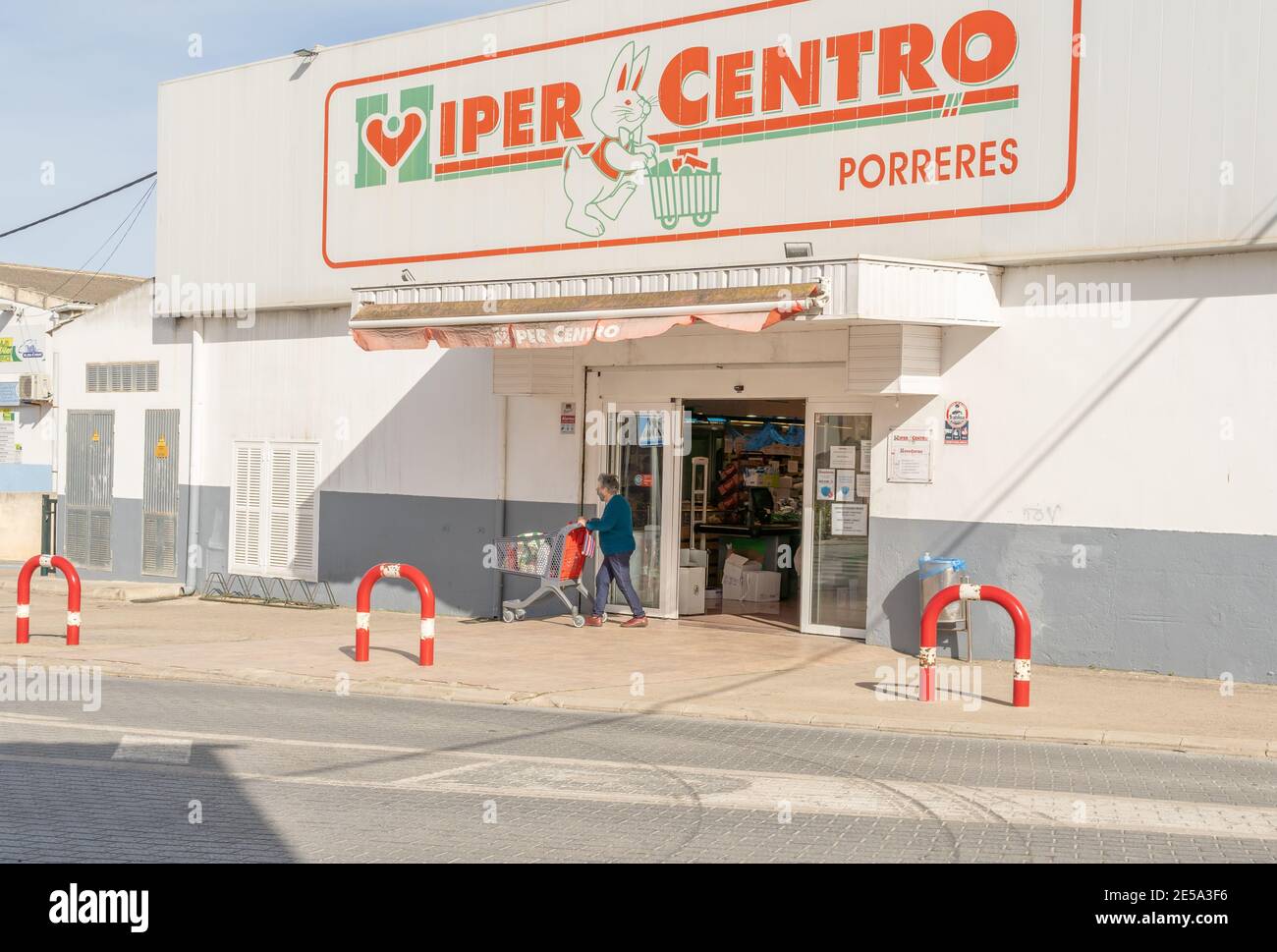 Porreres, Spanien; januar 21 2021: Hauptfassade des Supermarkts Hipercentro in der mallorquinischen Stadt Porreres. Ältere Frau, die mit einem Einkaufswagen abfährt Stockfoto