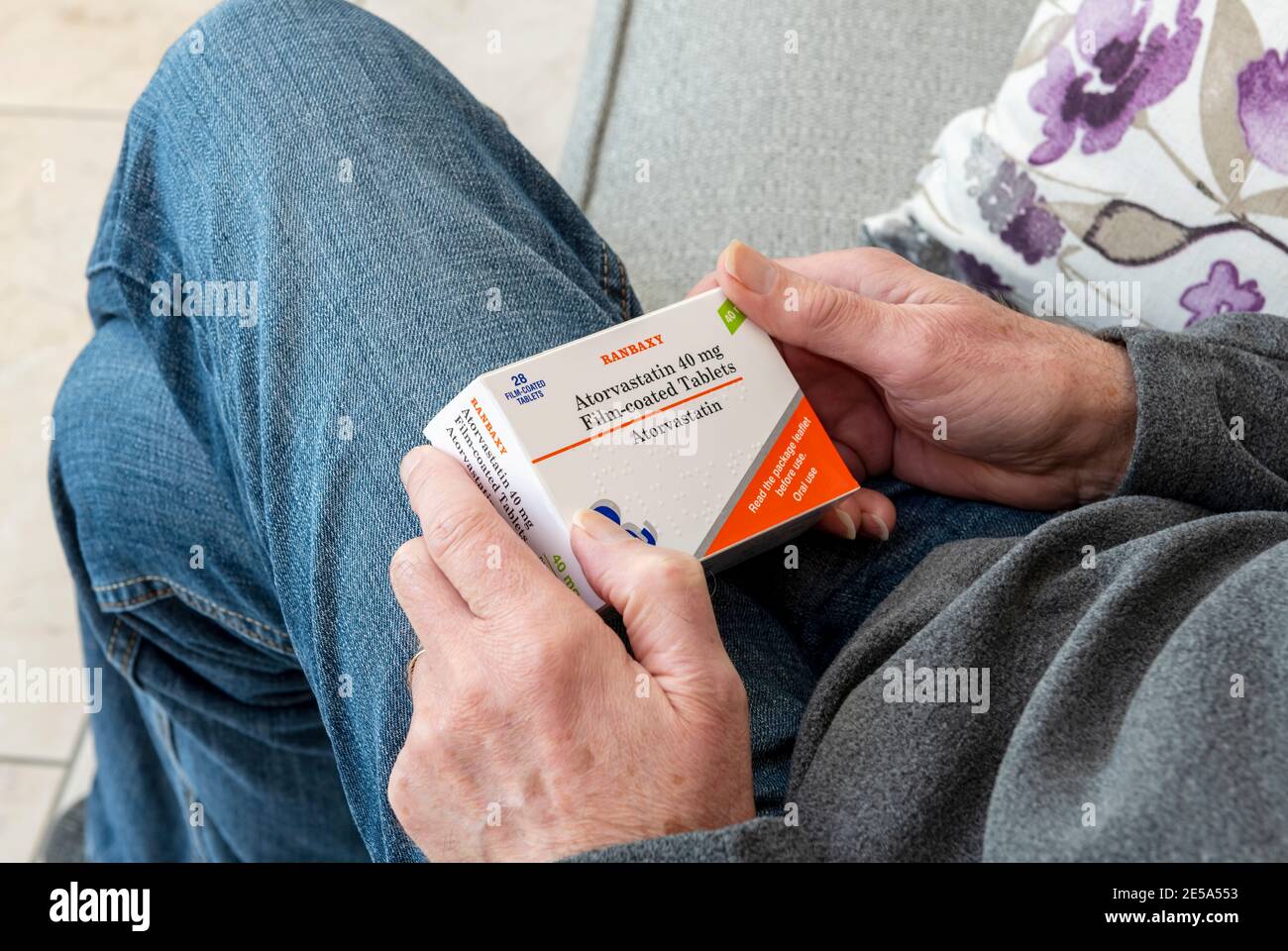 Nahaufnahme eines Mannes, der eine Schachtel Atorvastatin Tabletten hält Stockfoto
