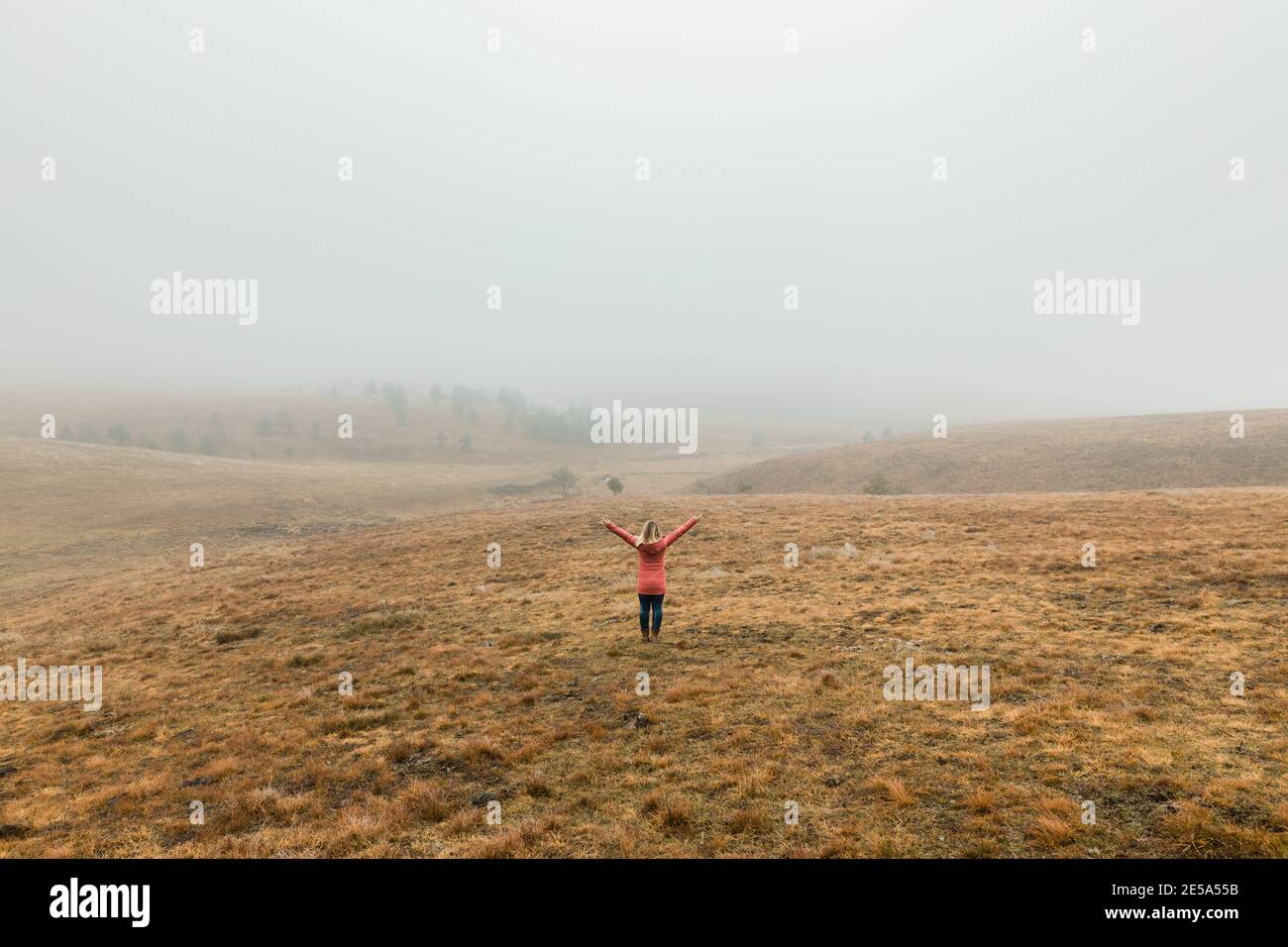 Junge Frau, die die Natur an einem nebligen Wintermorgen erkundet Stockfoto