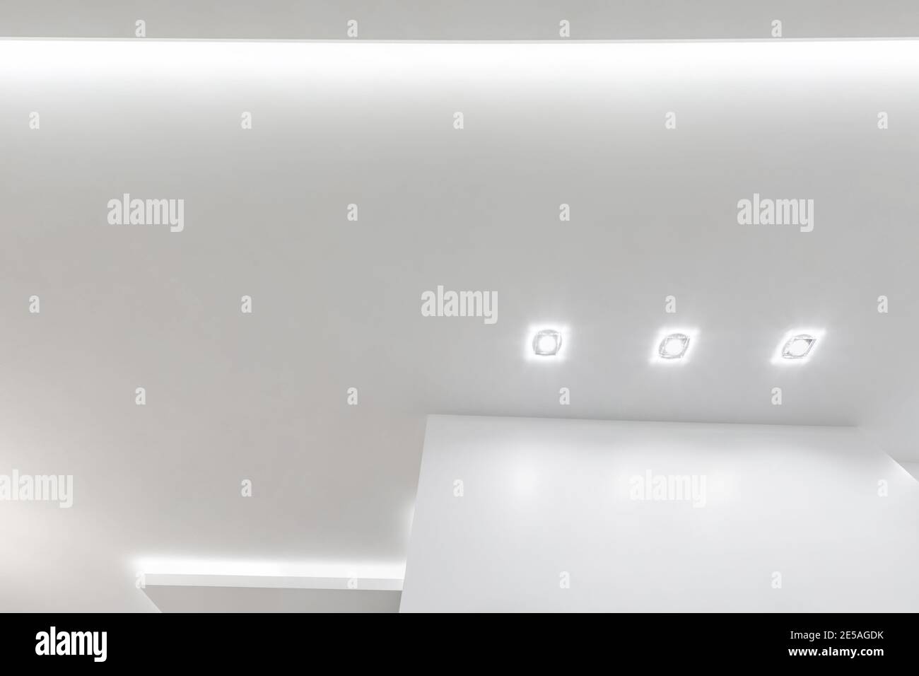 Blick auf die abgehängte Decke mit Halogenstrahlern und Trockenmauerkonstruktion im leeren Raum in Wohnung oder Haus. Stretchdecke weiß und kpl Stockfoto