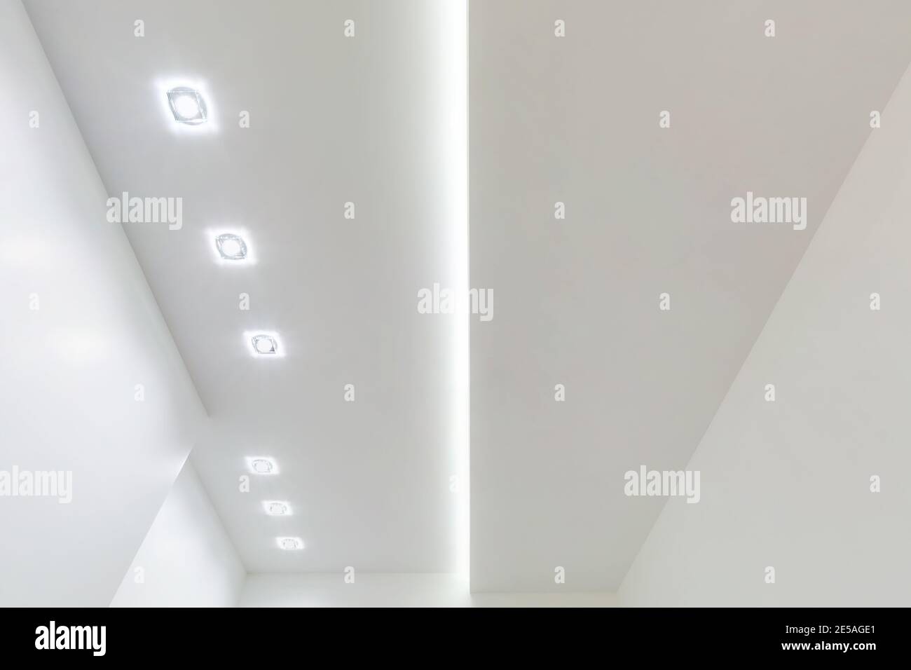 Blick auf die abgehängte Decke mit Halogenstrahlern und Trockenmauerkonstruktion im leeren Raum in Wohnung oder Haus. Stretchdecke weiß und kpl Stockfoto